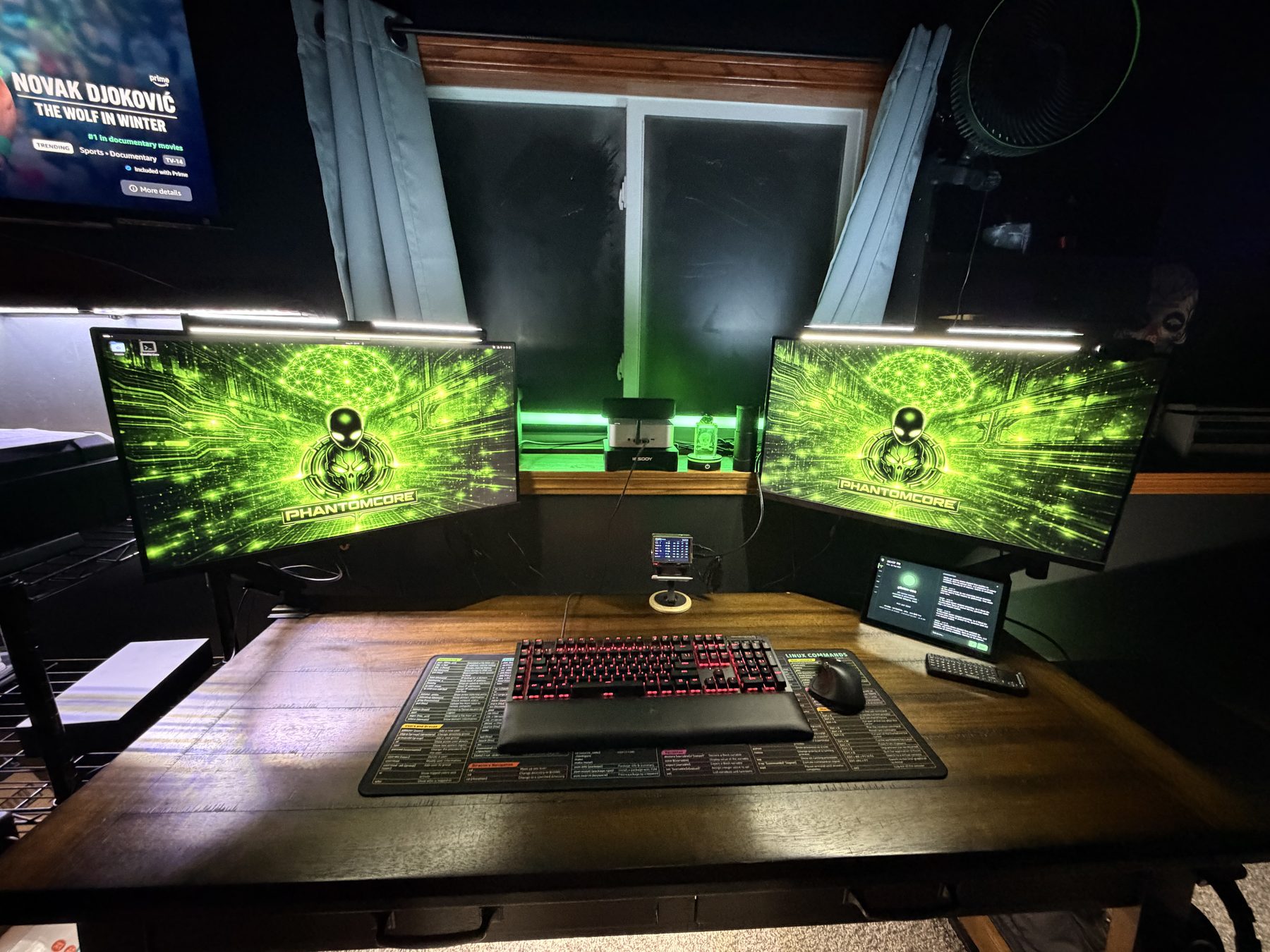 The PHNTM build desk — two monitors glowing green with the Phantomcore mark, a mechanical keyboard, and the phntm-one prototype