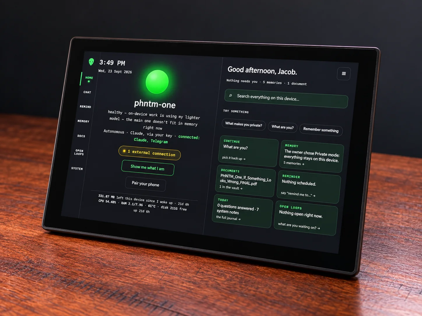 PHNTM One from a low three-quarter angle on a wooden desk, the green orb glowing on screen